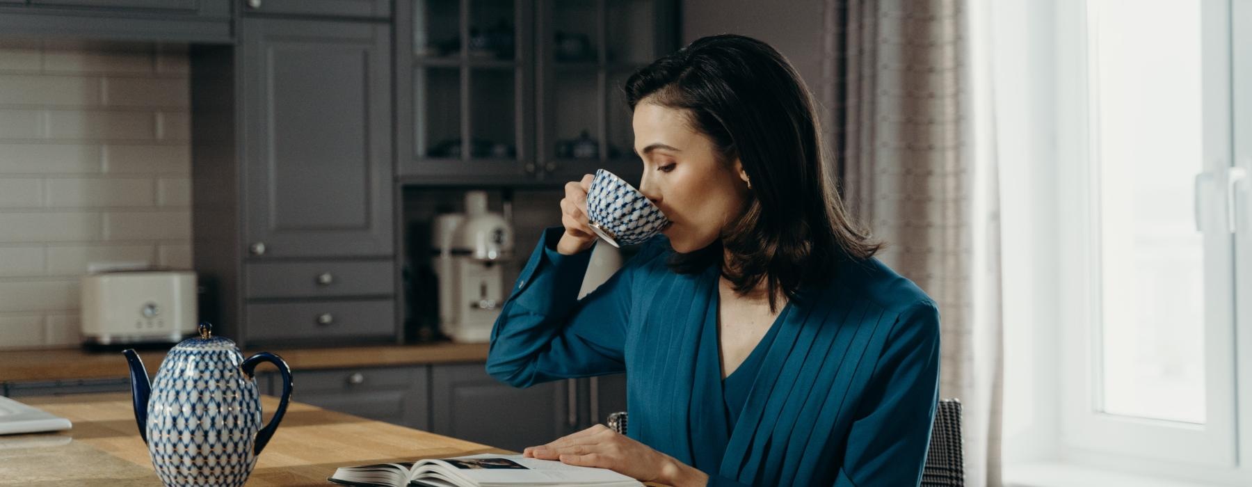 a person sitting at a table drinking from a cup
